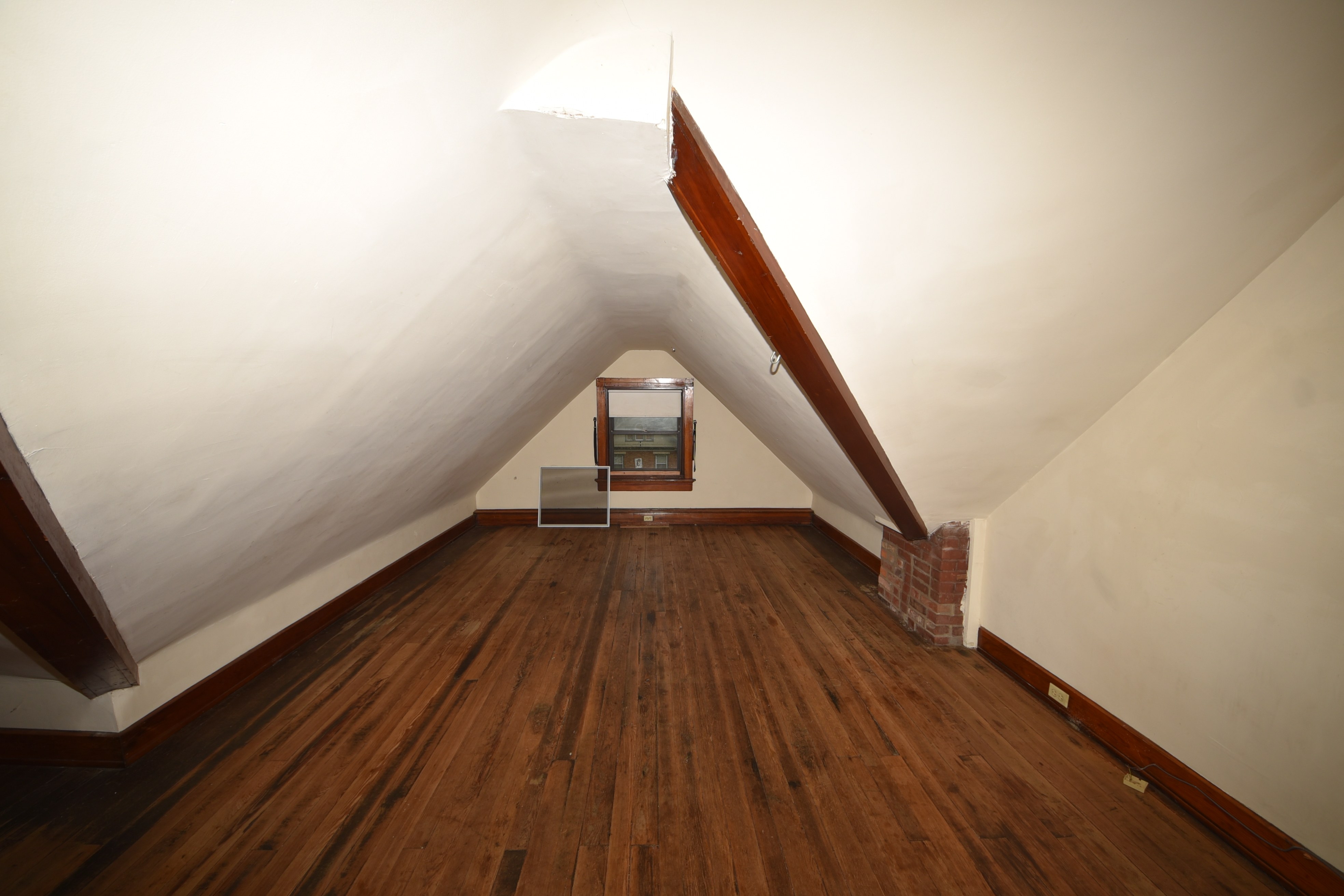 Attic room with window, sloped ceiling, and wood floor