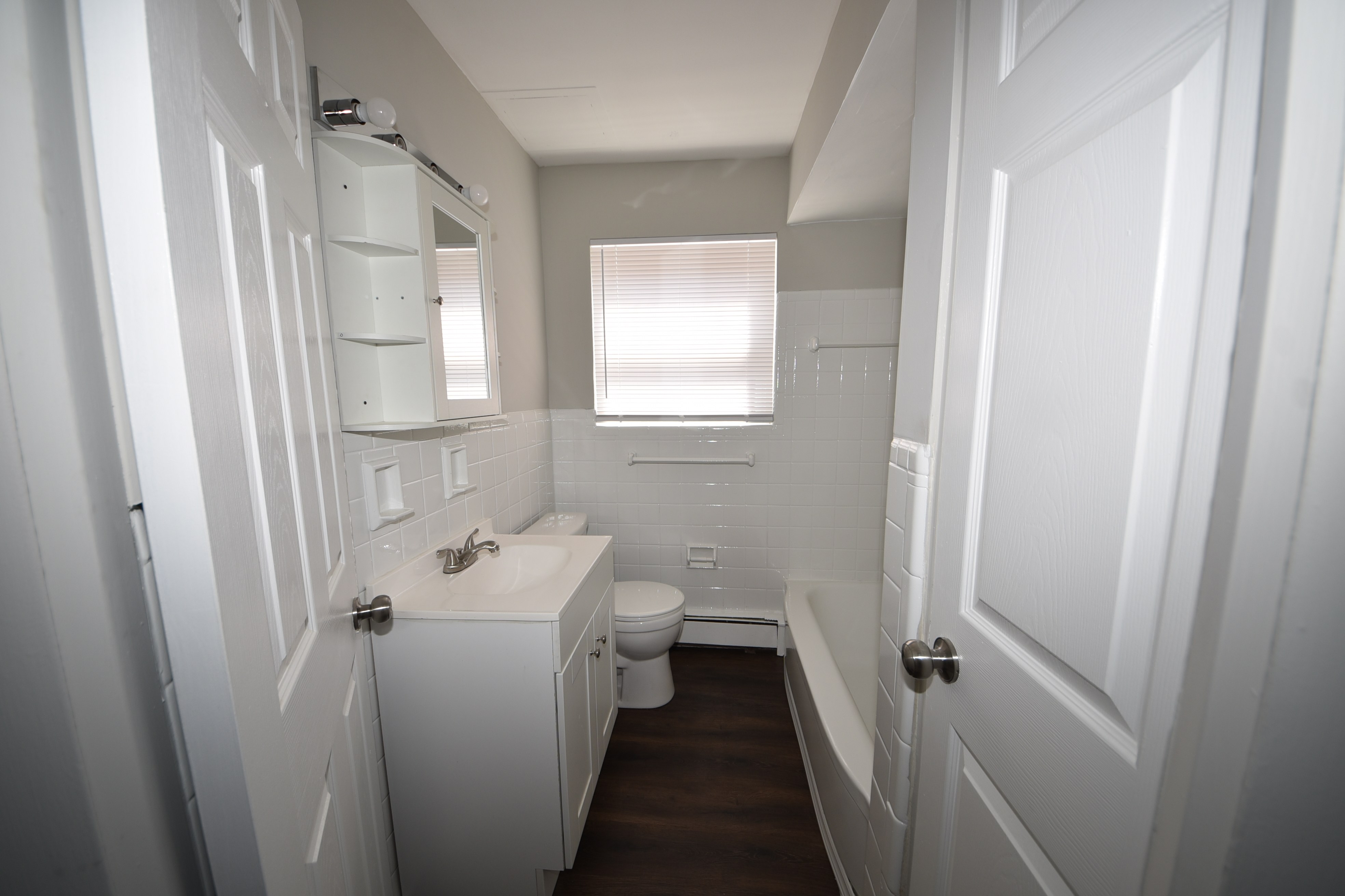 Bathroom with tub, white tile, vanity, and window