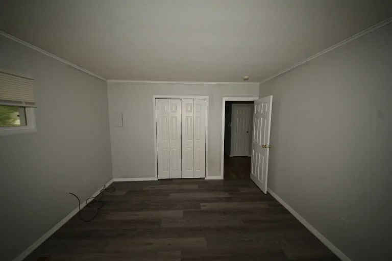 Bedroom with wide double-door closet and wood-look flooring