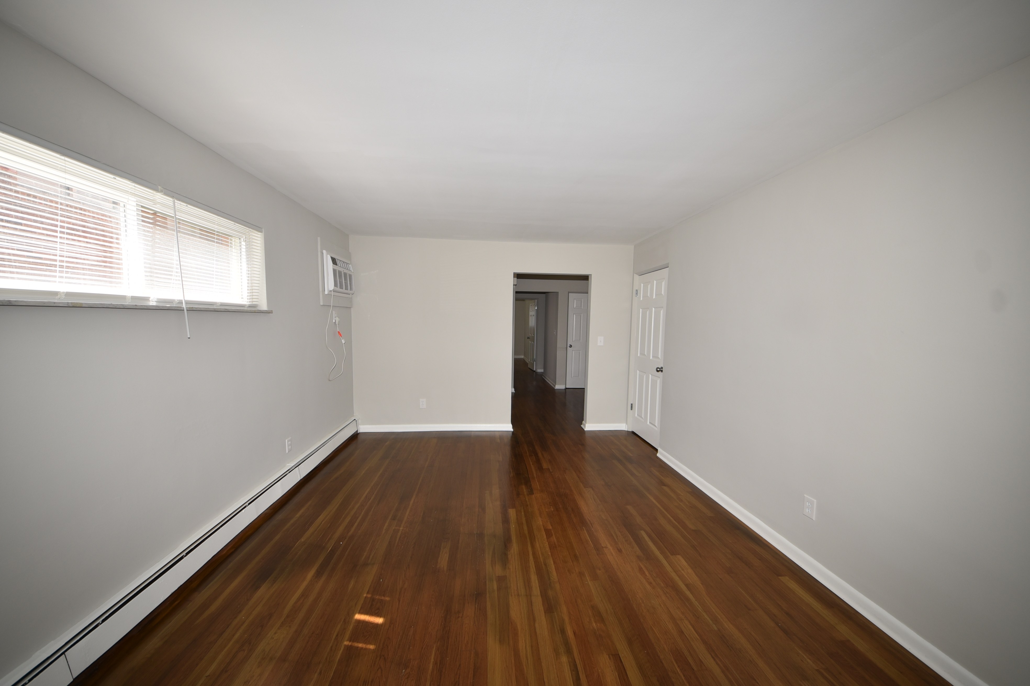 Living room with hardwood floors and wall air conditioner