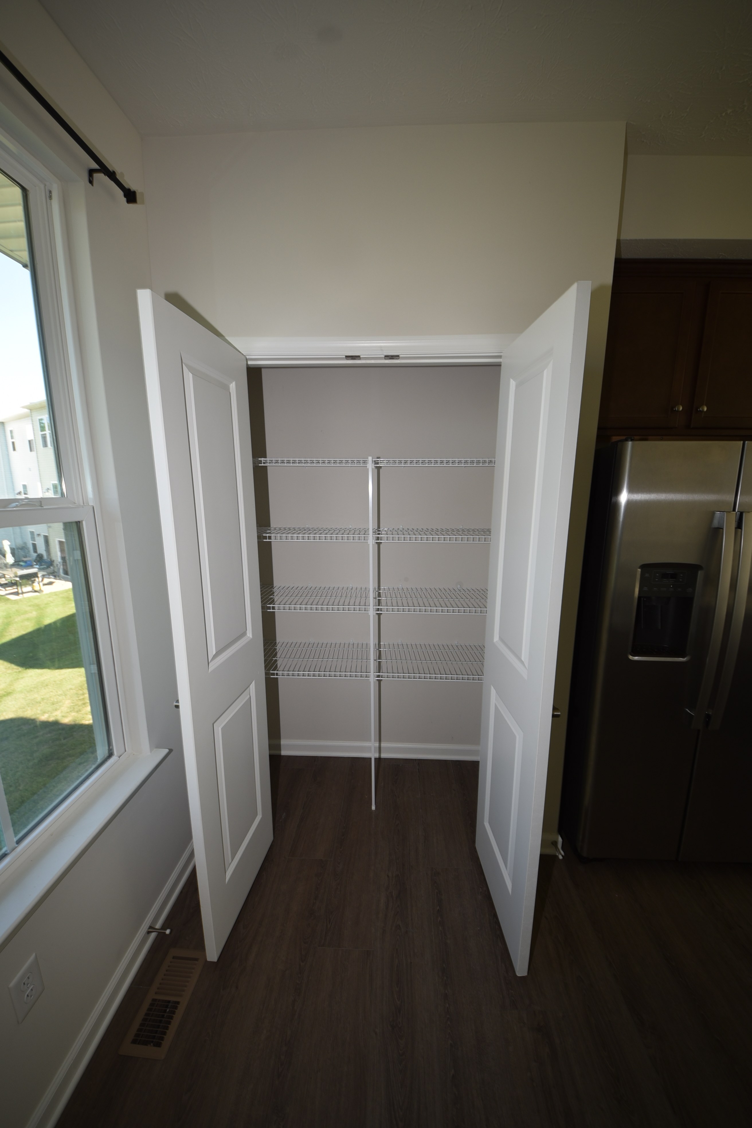 Pantry shelves beside stainless steel refrigerator