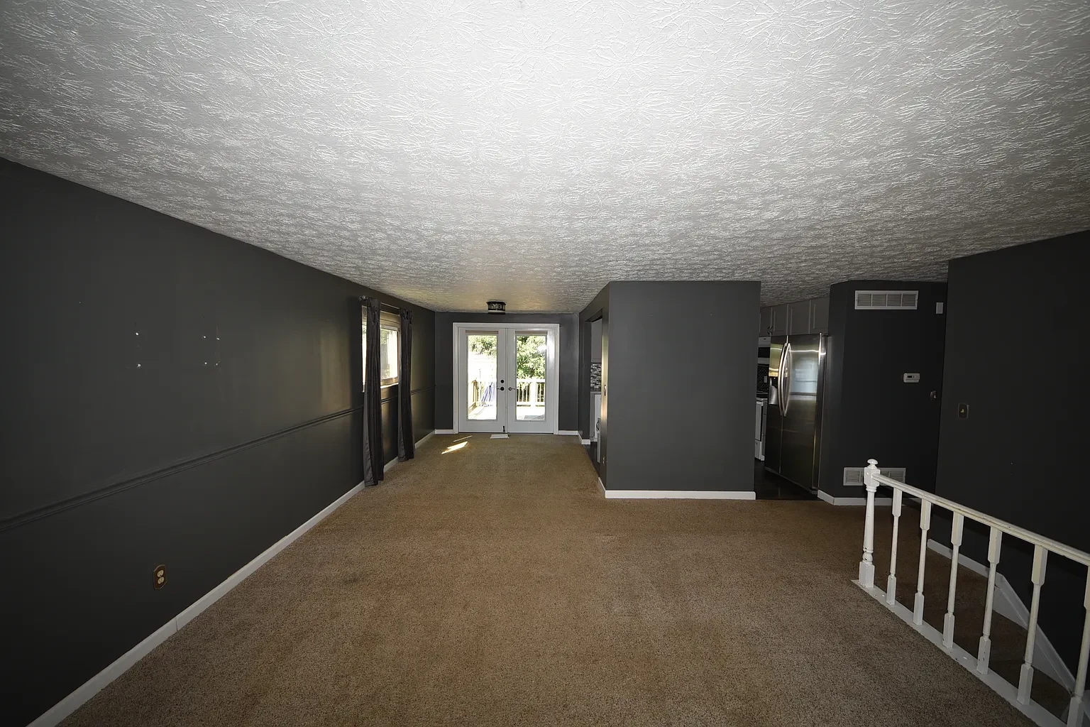 Living area with carpet, dark walls and stair railing