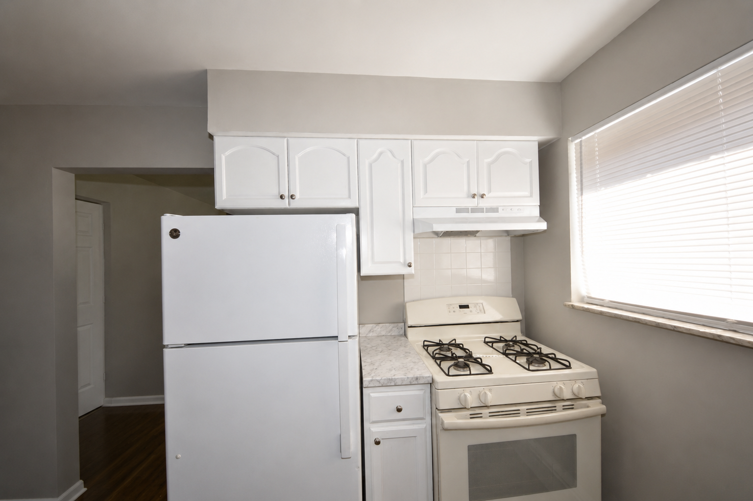 Kitchen with refrigerator, gas range, and white cabinets