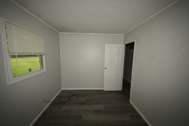 Bedroom with side window and wood-look flooring