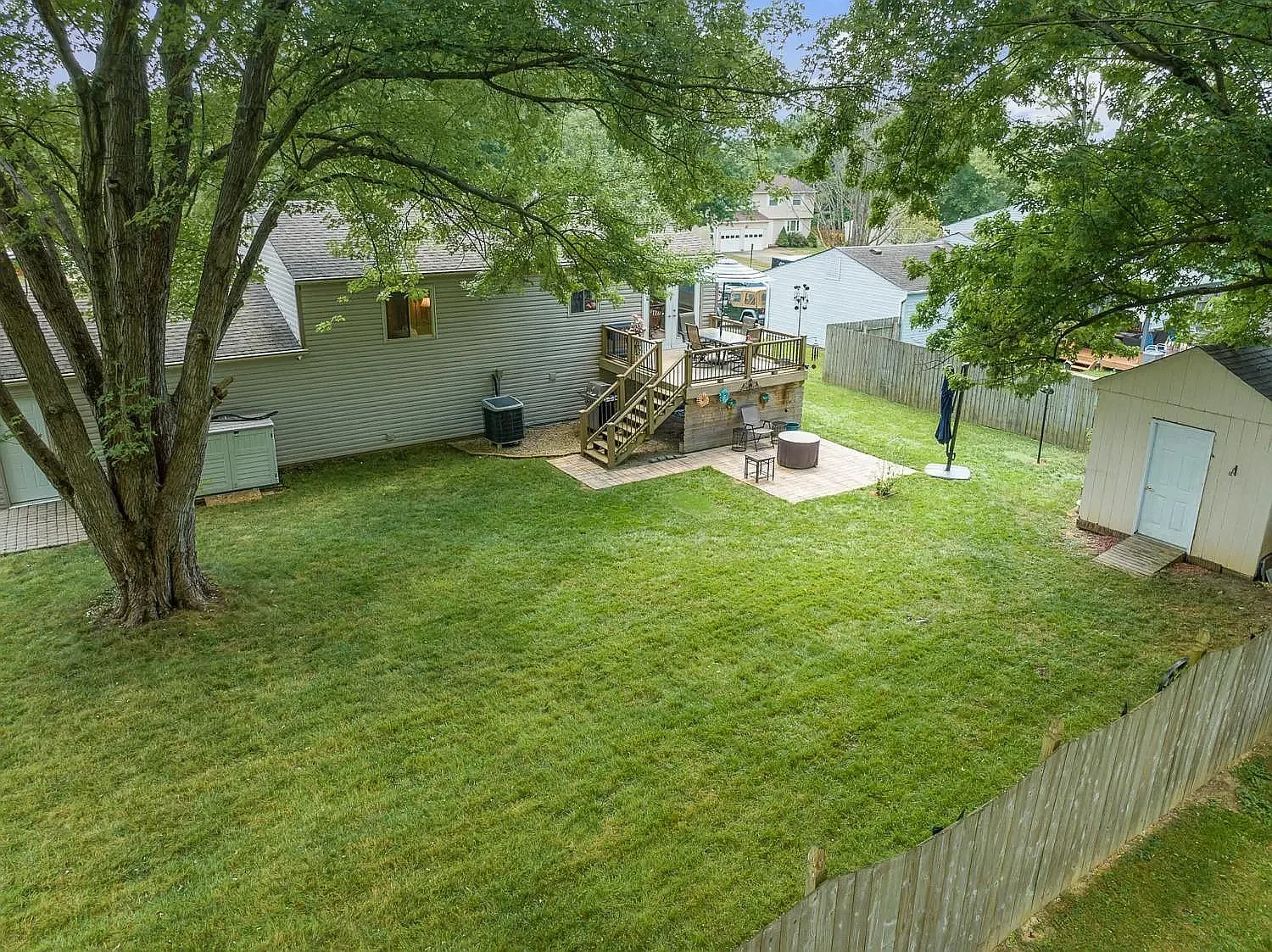 Fenced backyard with mature trees, deck and storage shed